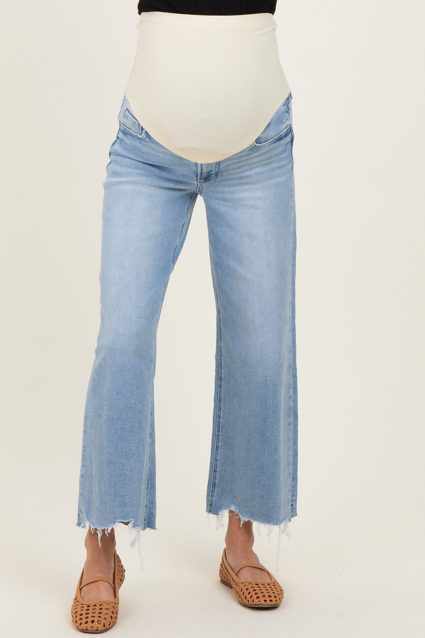 maternity wear light wash flared jeans with a cream colored over-the-bump panel and distressed hem