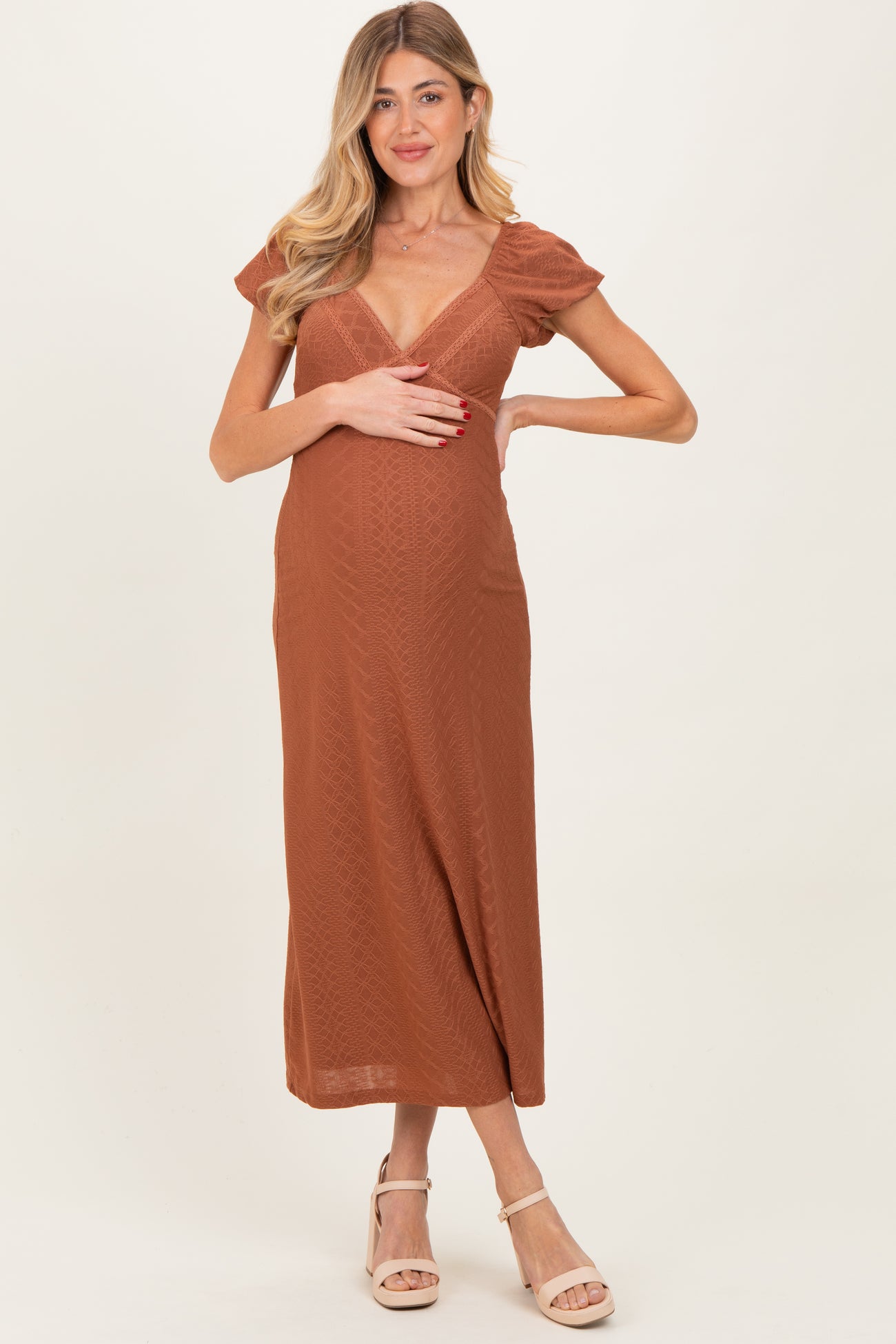 woman wearing a rust-colored short sleeve maternity dress and holding her baby bump