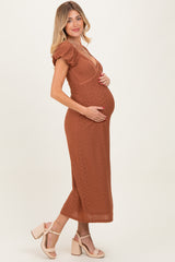 woman wearing a rust-colored maternity dress with v-neck and short puff sleeves, displaying her baby bump