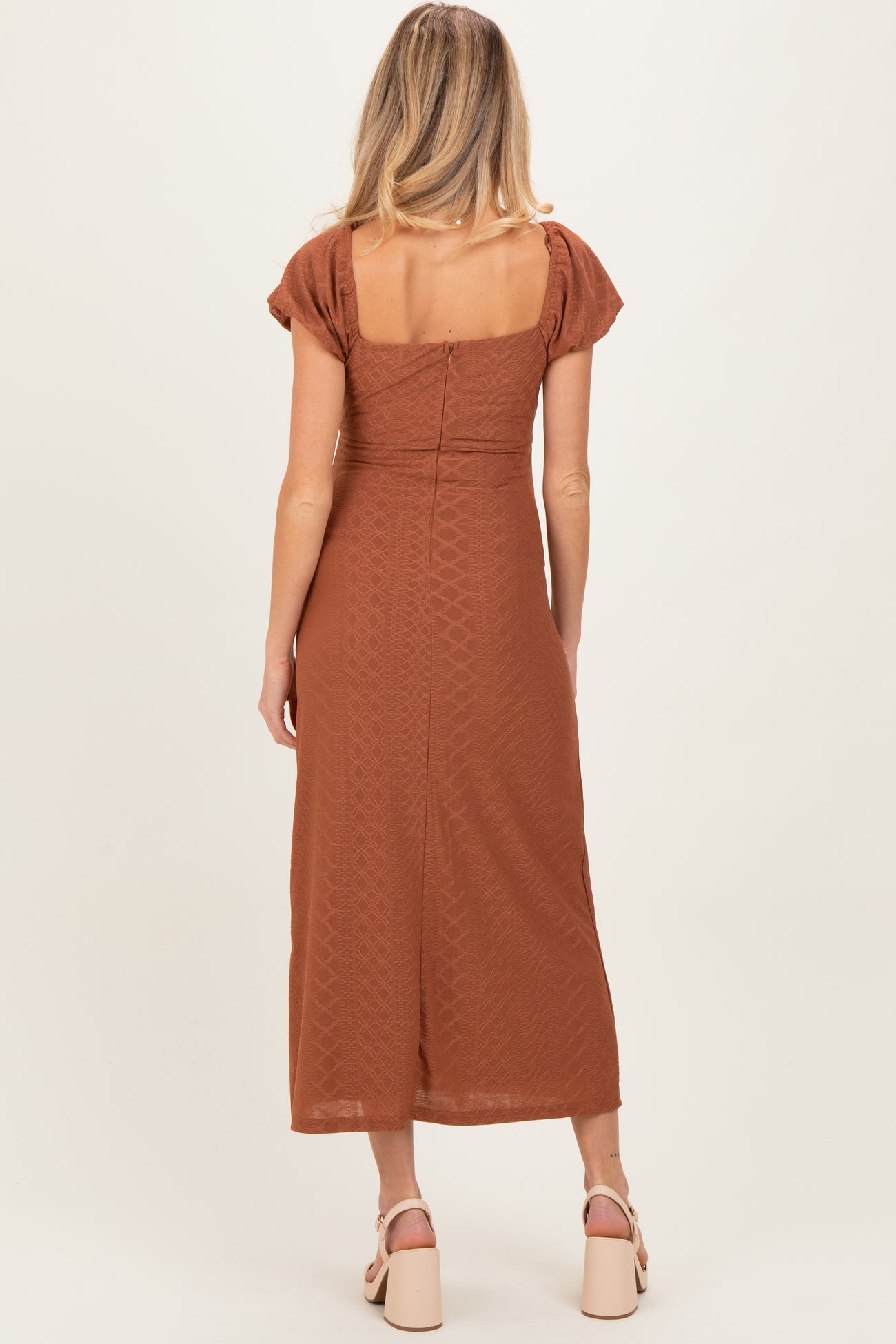 woman wearing a rust-colored midi maternity dress with short puff sleeves and a square back design