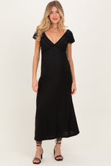 woman wearing a black maternity dress with a deep v-neckline and short puff sleeves, highlighting her baby bump