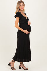 woman wearing a black maternity dress with short puff sleeves and a v-neck, holding her baby bump