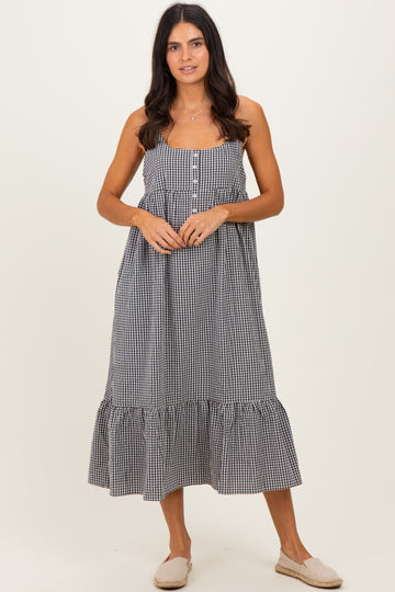 woman wearing a black and white gingham maxi dress with buttons and a ruffled hem, standing on a neutral background