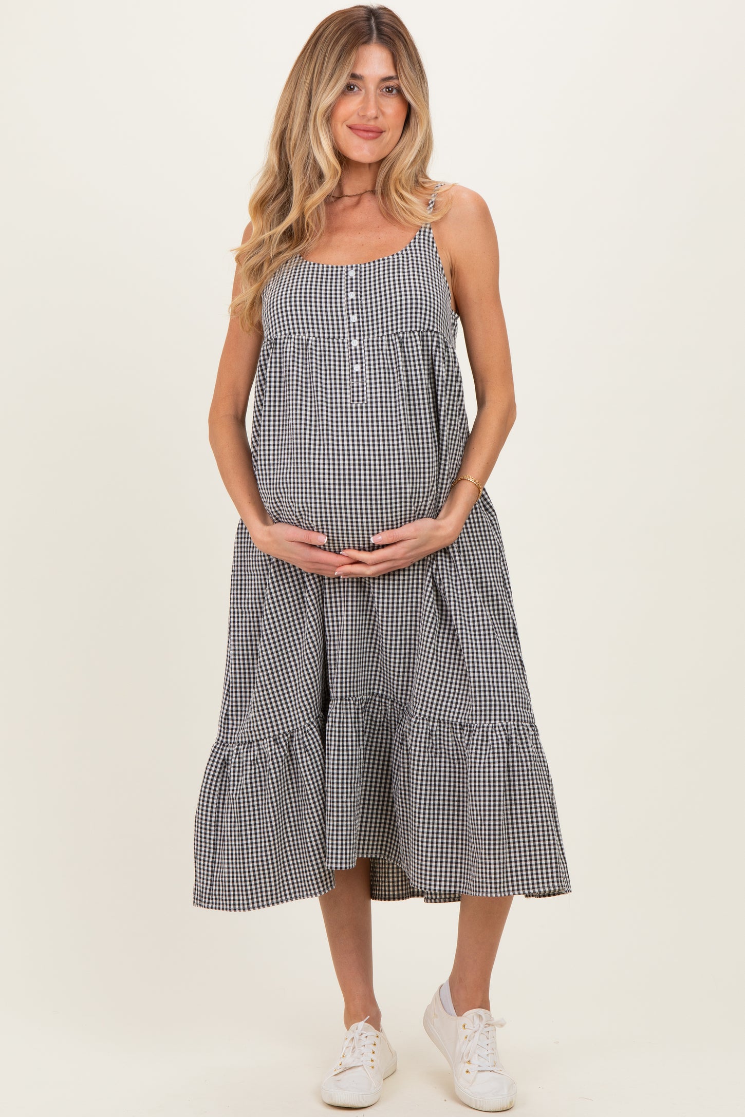 woman wearing a black and white gingham maternity dress with a tiered skirt and holding her baby bump