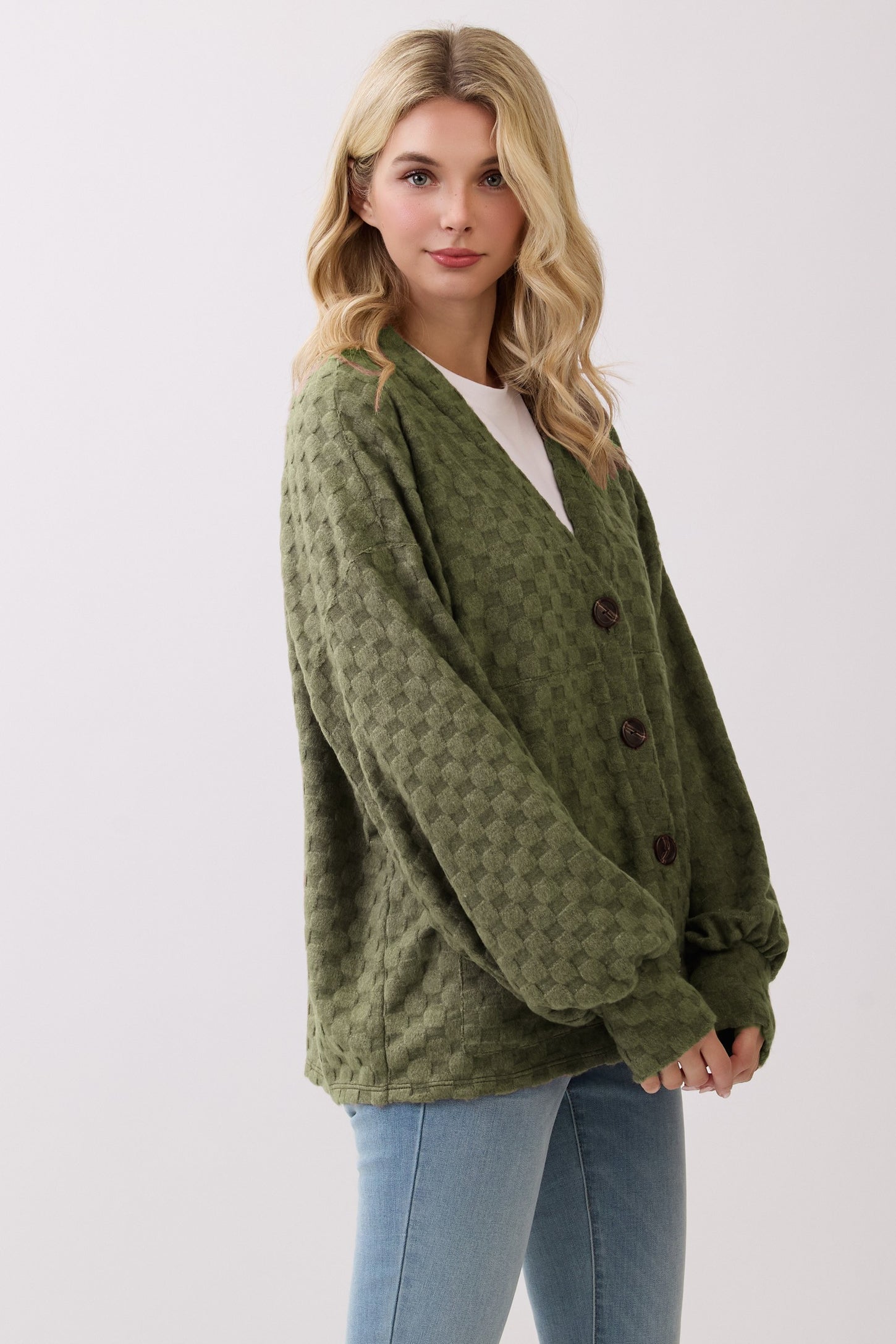 woman wearing a green textured oversized cardigan with buttons and styled with a white t-shirt and light blue jeans