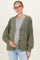 woman wearing an olive green checkerboard maternity cardigan and a grey top, holding her baby bump