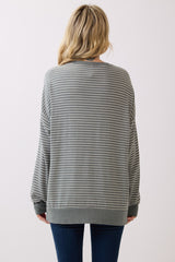 woman wearing a gray and white striped oversized sweatshirt, viewed from the back, paired with dark blue jeans
