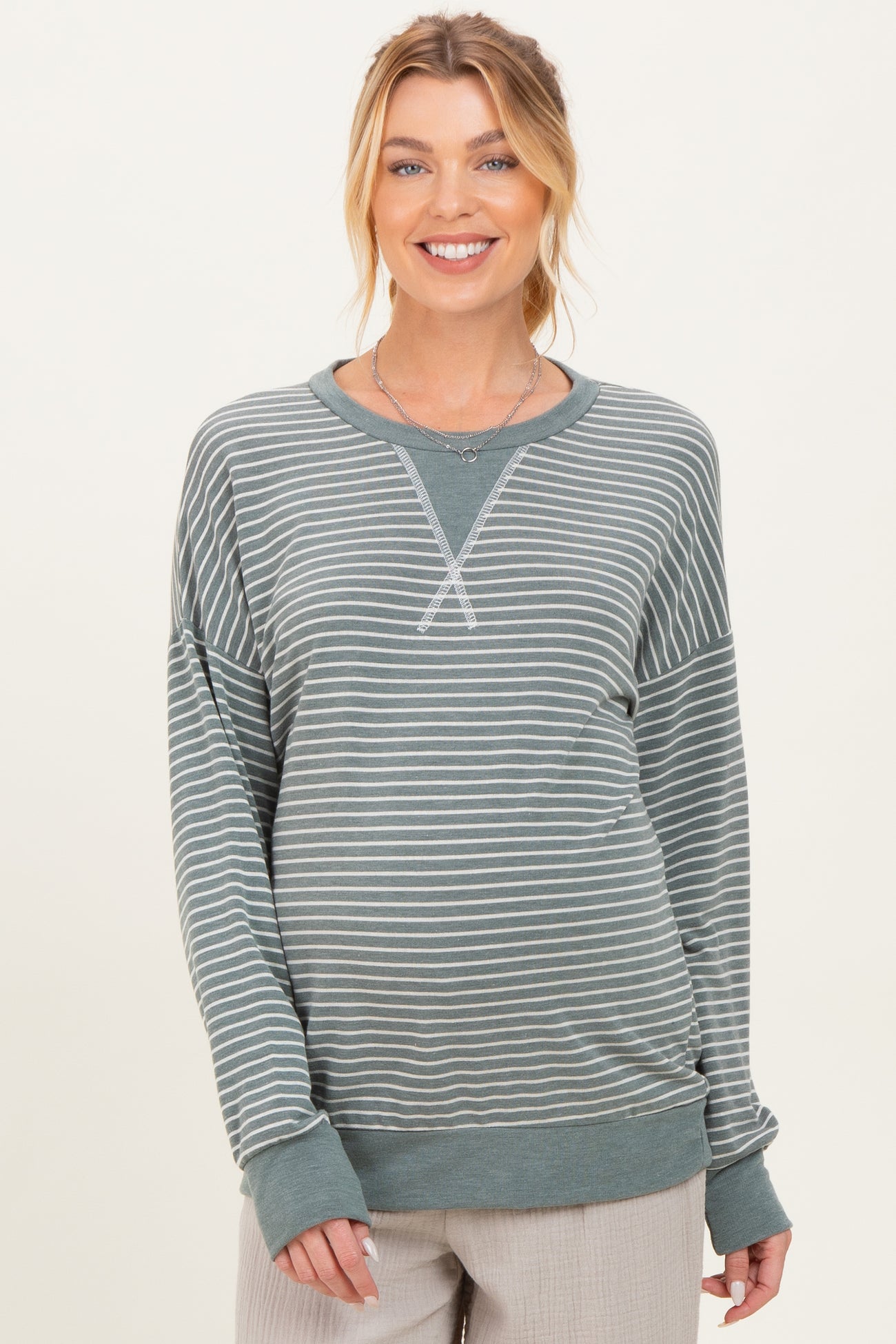 woman wearing a green striped maternity sweatshirt with long sleeves and a relaxed fit, showing her baby bump