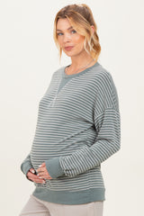 woman wearing a green striped maternity sweatshirt and holding her baby bump