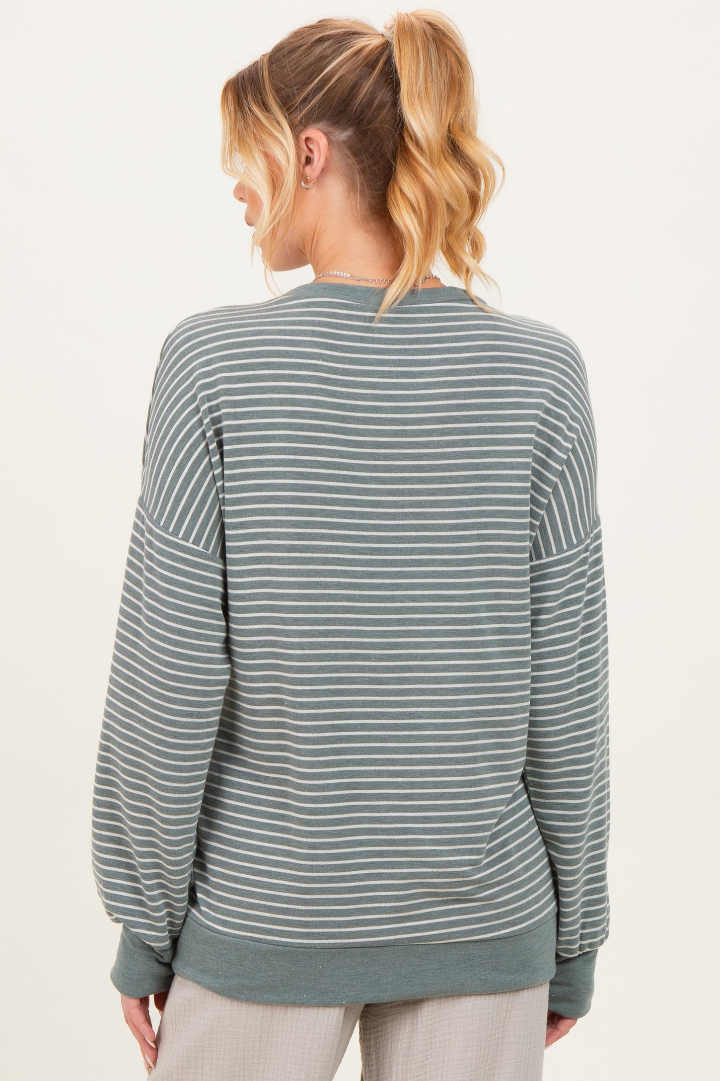woman wearing a green striped maternity sweatshirt with long sleeves, shown from the back