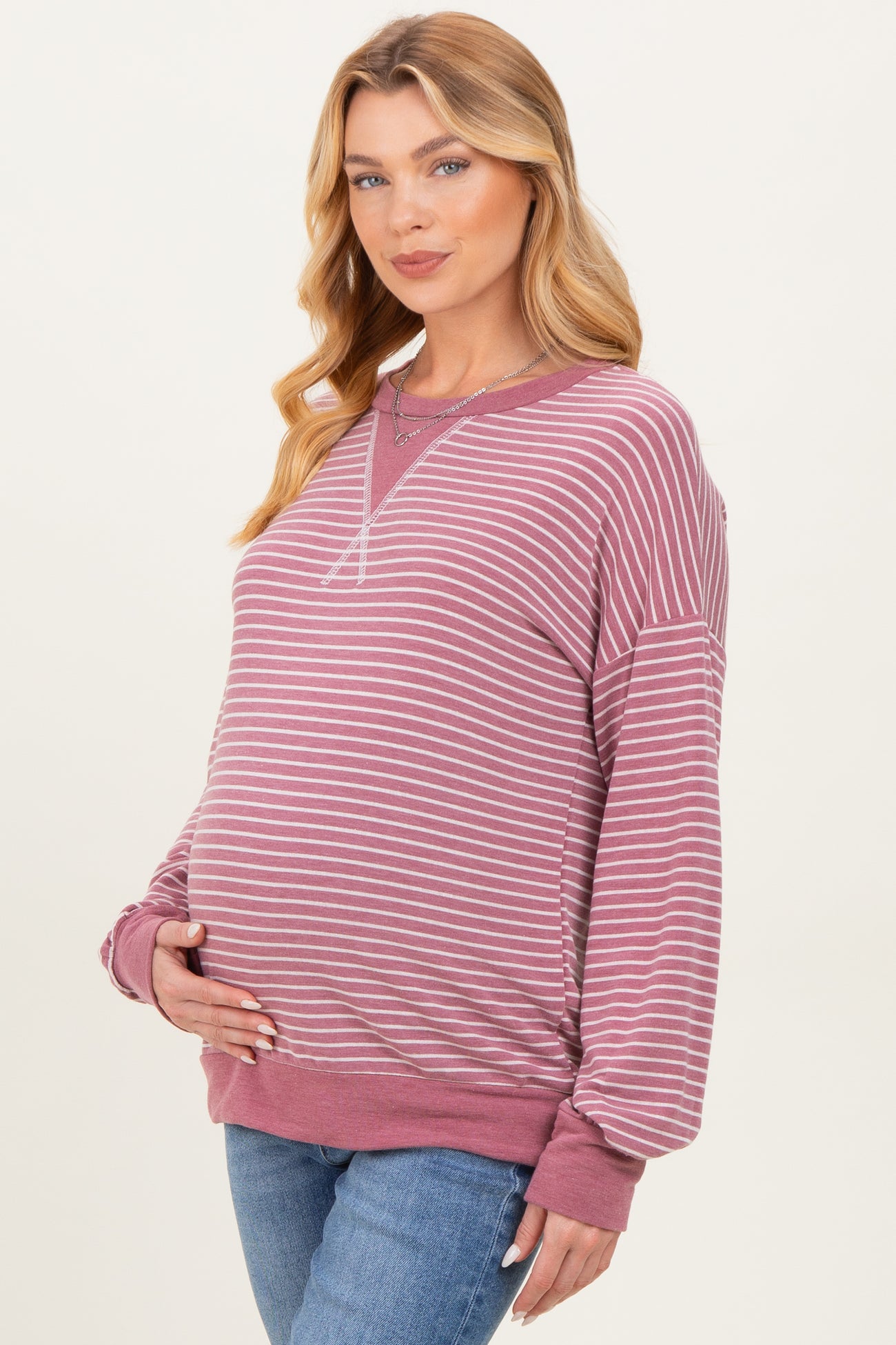 woman wearing a pink and white striped maternity sweatshirt with a visible baby bump