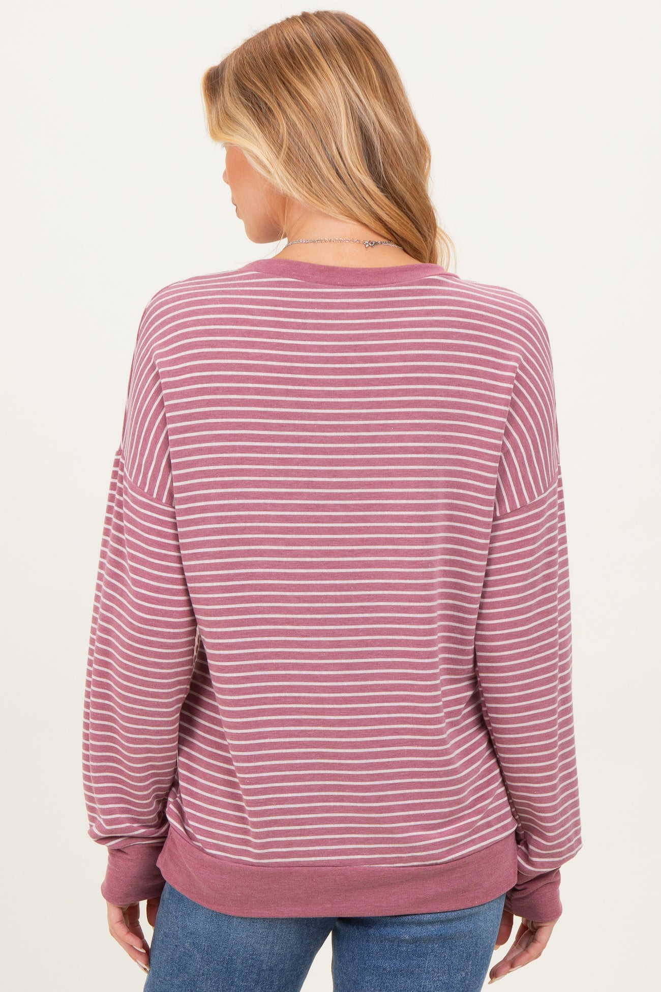 woman wearing a mauve and white striped maternity sweatshirt with a relaxed fit seen from the back