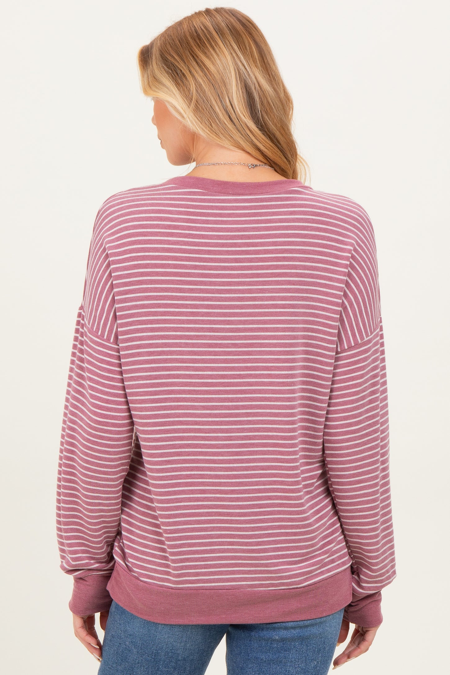 woman wearing a mauve and white striped maternity sweatshirt with a relaxed fit seen from the back