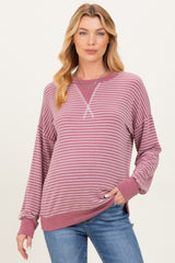 woman wearing a burgundy and white striped maternity sweatshirt with a relaxed fit and long sleeves