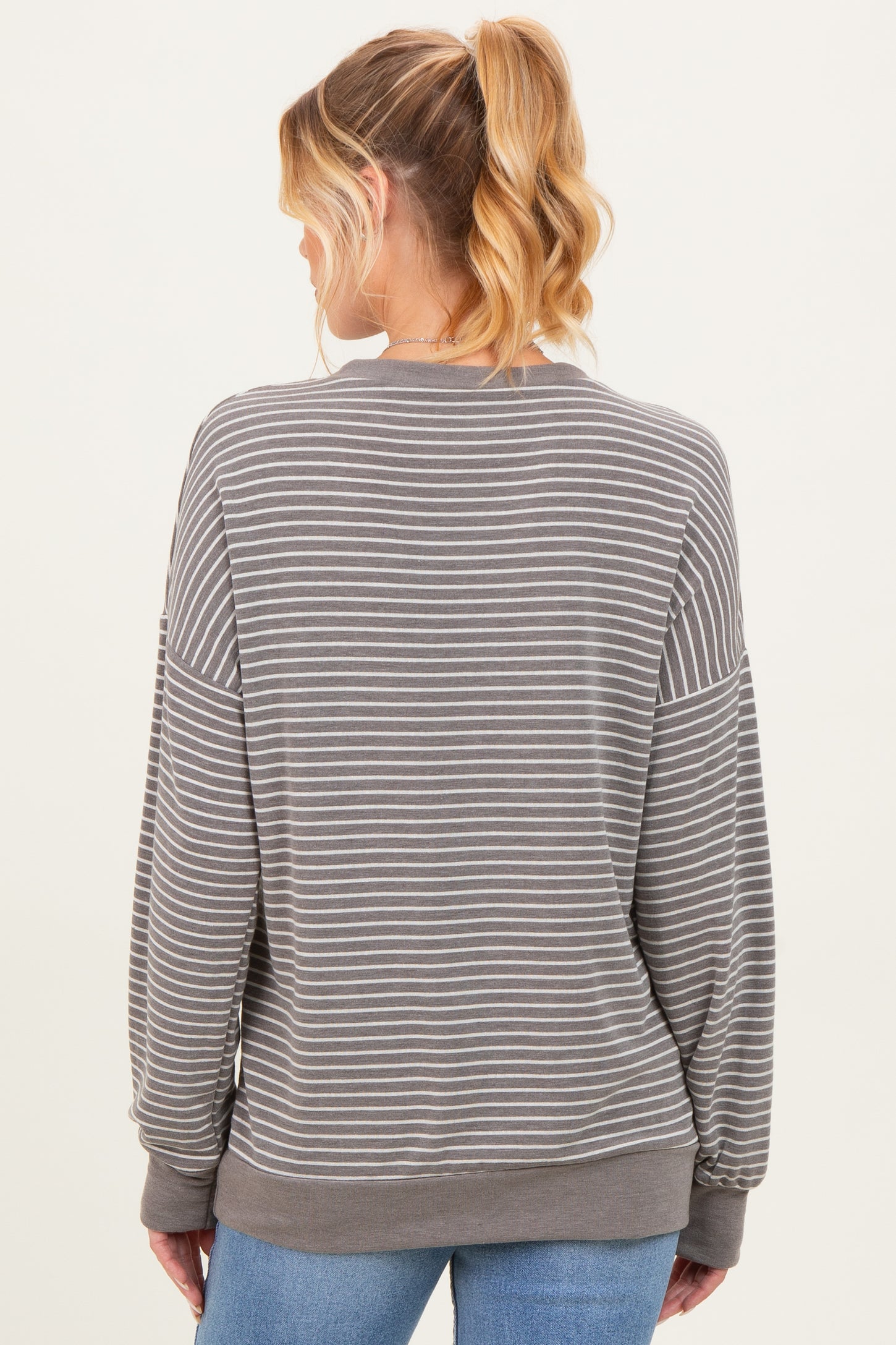 woman wearing a gray striped maternity sweatshirt seen from the back, with loose fit and long sleeves