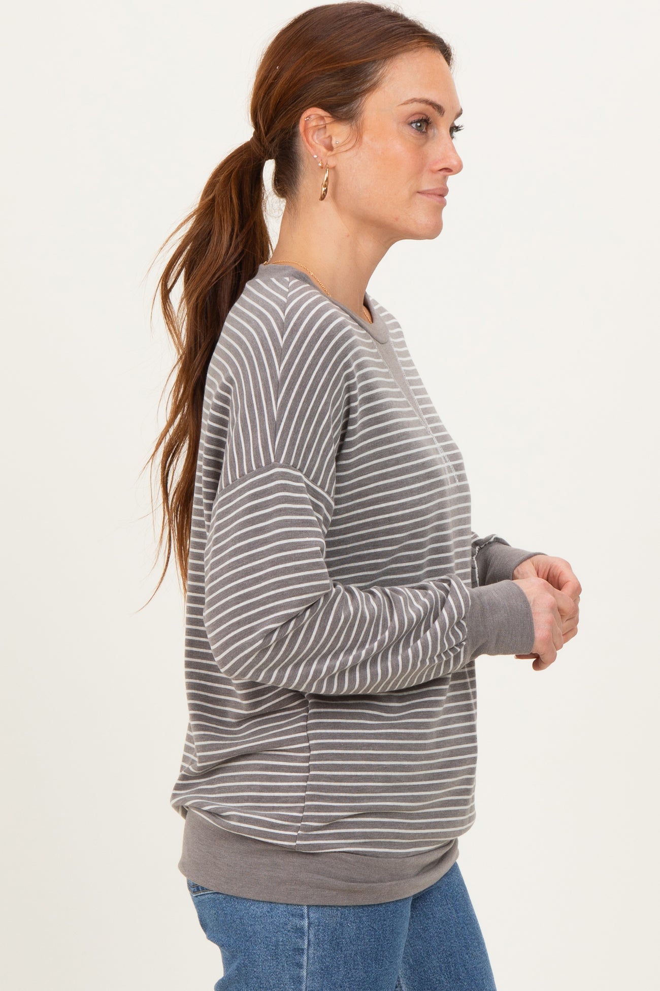 woman wearing a gray and white striped long sleeve sweatshirt with a relaxed fit and ribbed cuffs