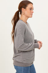 woman wearing a gray and white striped long sleeve sweatshirt with a relaxed fit and ribbed cuffs