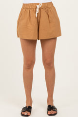 woman wearing light brown drawstring shorts with pockets and black slide sandals