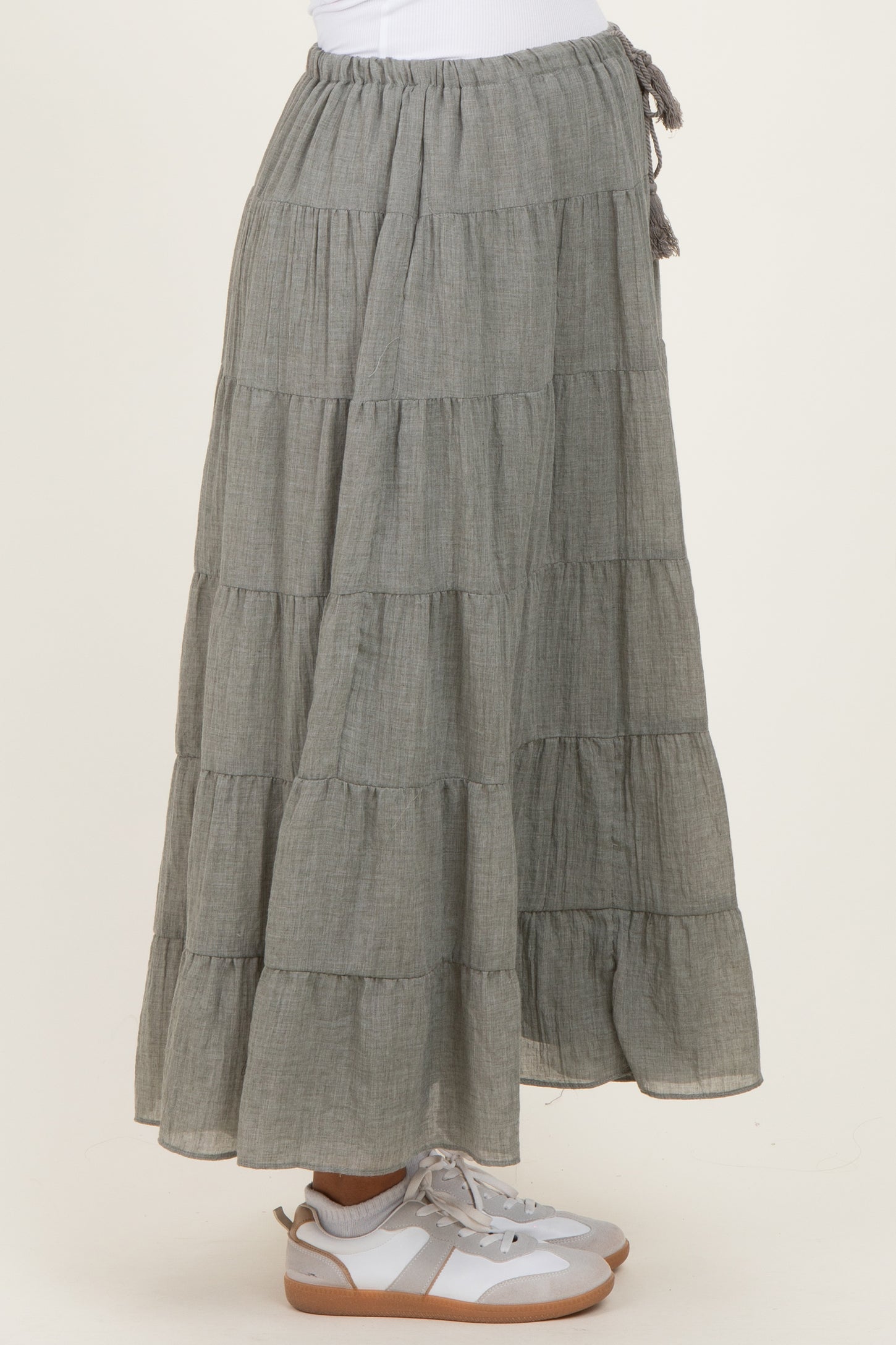 woman wearing a gray tiered maternity maxi skirt with a drawstring waist and paired with white sneakers