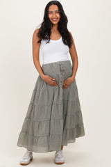 woman wearing a gray tiered maternity maxi skirt and a white tank top while holding her baby bump
