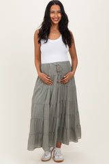 woman wearing a white tank top and a long gray tiered maternity skirt, holding her baby bump