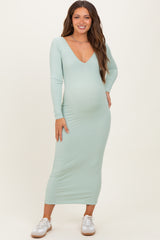 woman wearing a mint green ribbed long sleeve maternity dress and showing her baby bump
