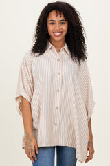 woman wearing a beige striped oversized shirt with short sleeves and button front, smiling at the camera