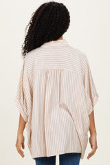 woman showing the back of a beige striped oversized blouse with short sleeves and a relaxed fit