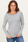 woman wearing a light gray long sleeve top and blue jeans, posing with hands on her hips