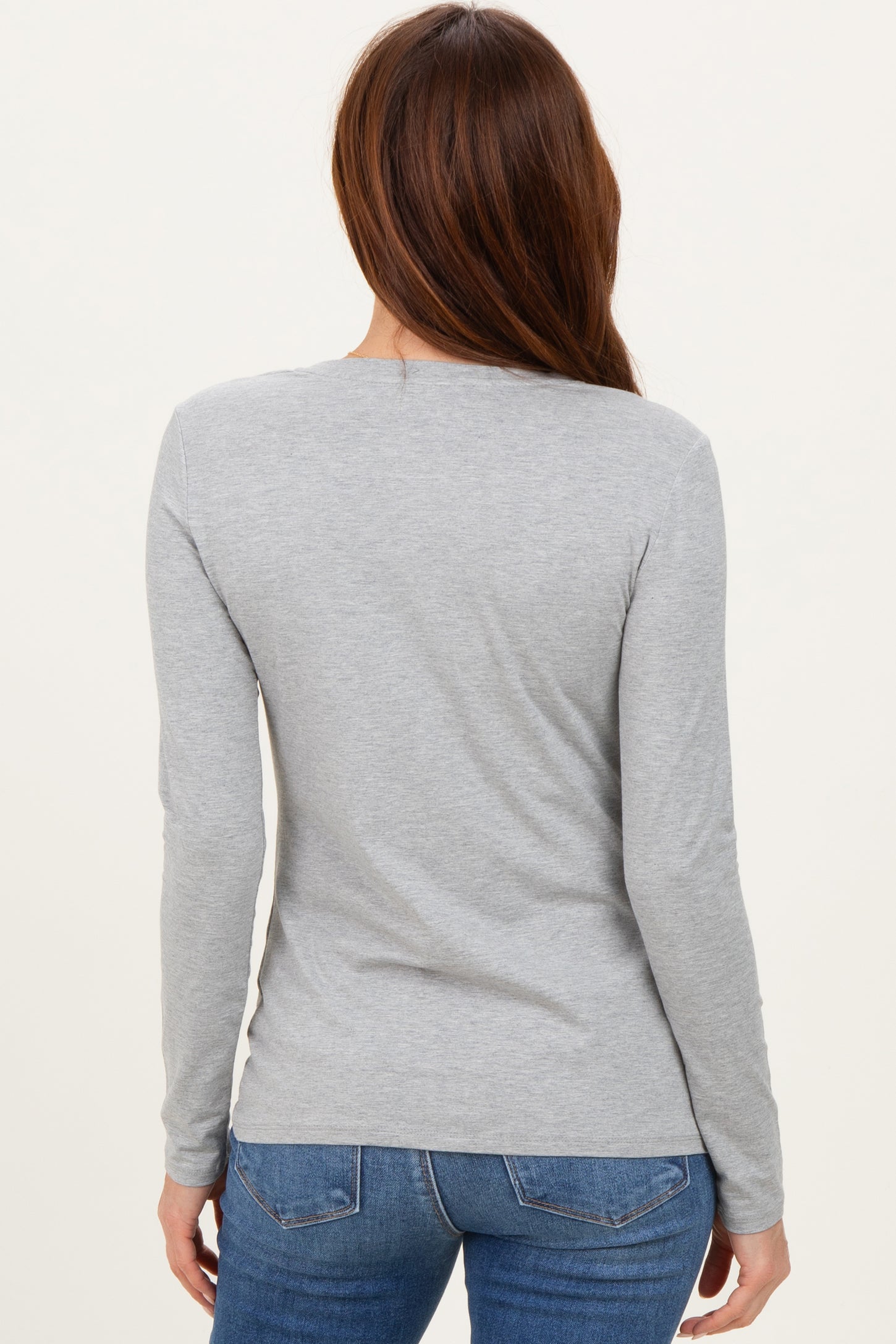 woman wearing a grey long sleeve top, viewed from the back, paired with blue jeans