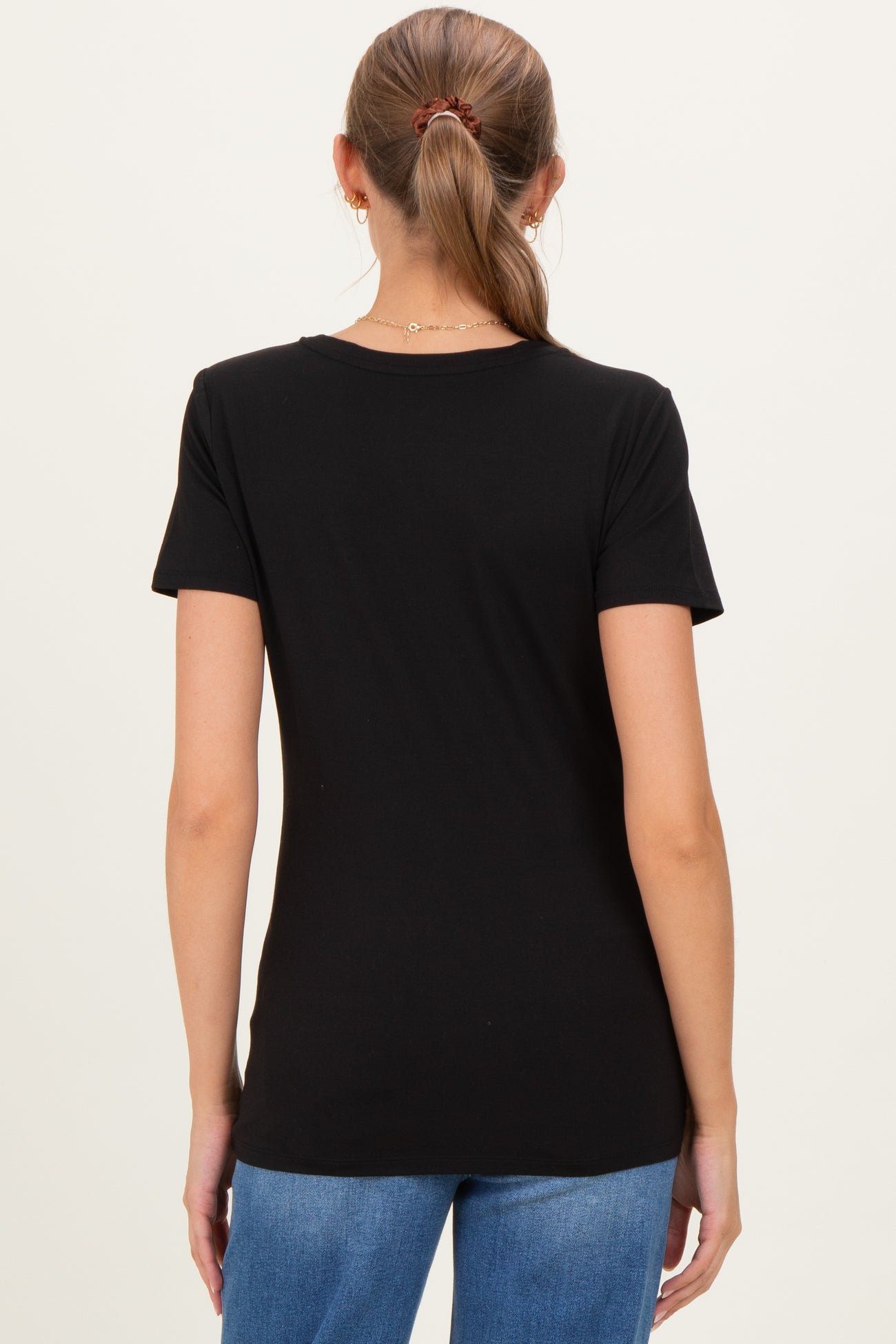 woman wearing a black short sleeve maternity top, seen from the back with her hair pulled back