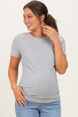 woman wearing a light gray short sleeve maternity top and showing her baby bump