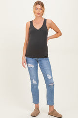 woman wearing a black maternity tank top and distressed blue jeans, showing a visible baby bump