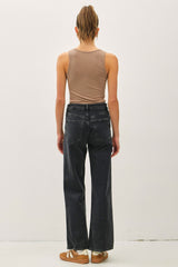 woman wearing a beige tank top and black wide-leg jeans, viewed from the back
