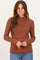 woman wearing a rust and cream striped long sleeve turtleneck sweater with a fitted style and round neckline