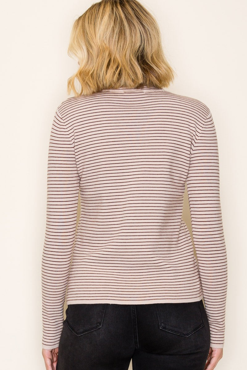 woman wearing a light beige striped long sleeve top and black jeans, viewed from the back