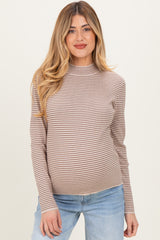 woman wearing a striped beige maternity top with a high neck and visible baby bump, paired with light blue jeans