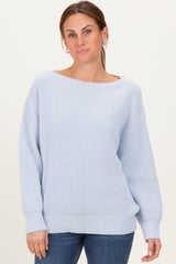 woman wearing a light blue oversized knit sweater with a wide neckline and long sleeves, paired with jeans
