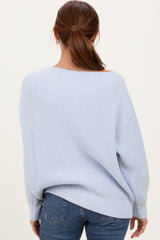 woman wearing a light blue oversized knit sweater from the back with a relaxed fit and wide neckline