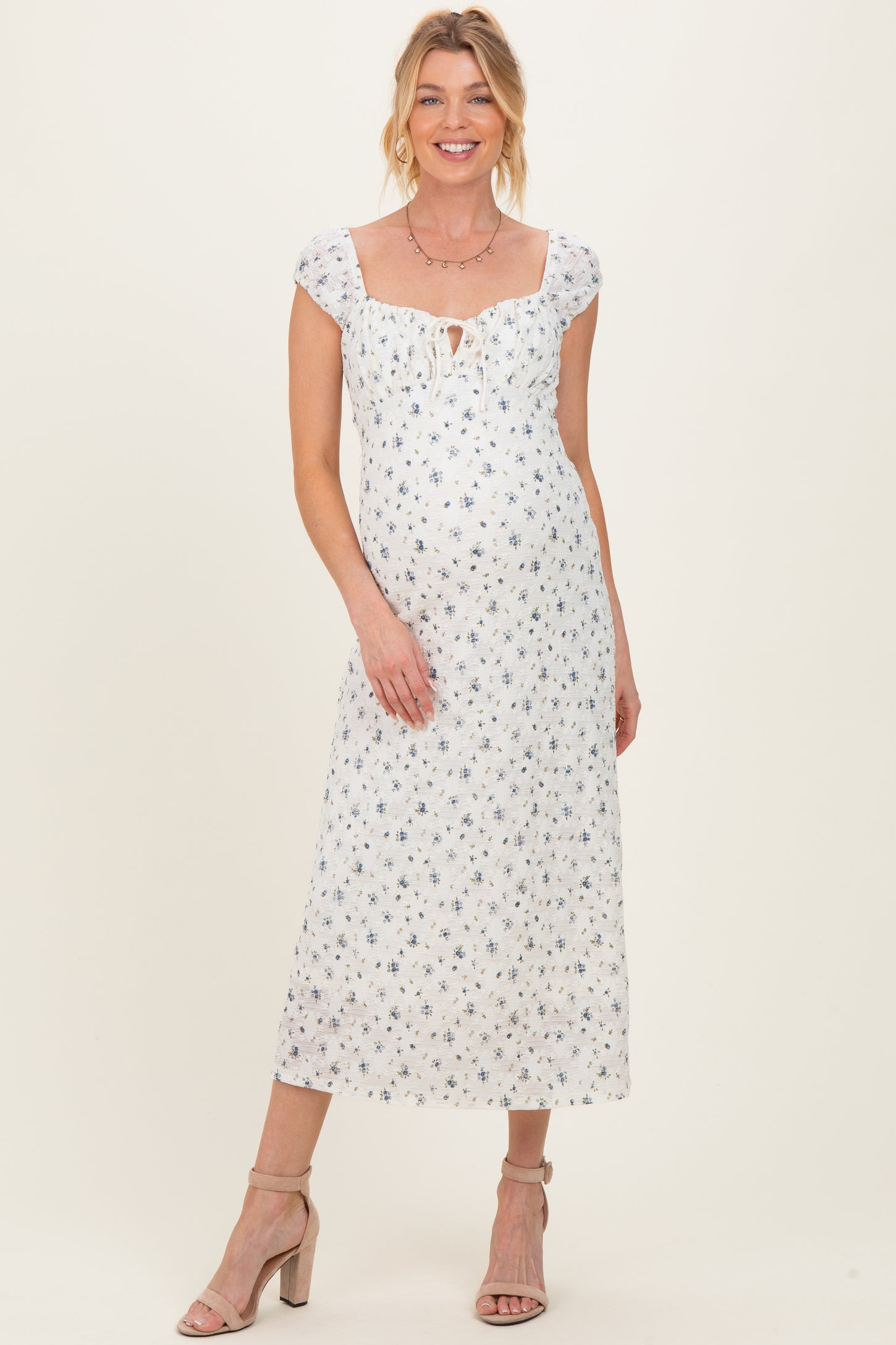 woman wearing a white floral maternity dress with a square neckline and a baby bump