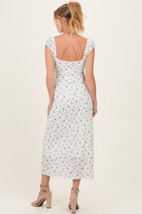 woman wearing a white maternity dress with blue floral print and short sleeves, shown from the back