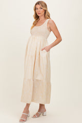 woman wearing a beige maternity dress with tiered design and pockets, showing her baby bump