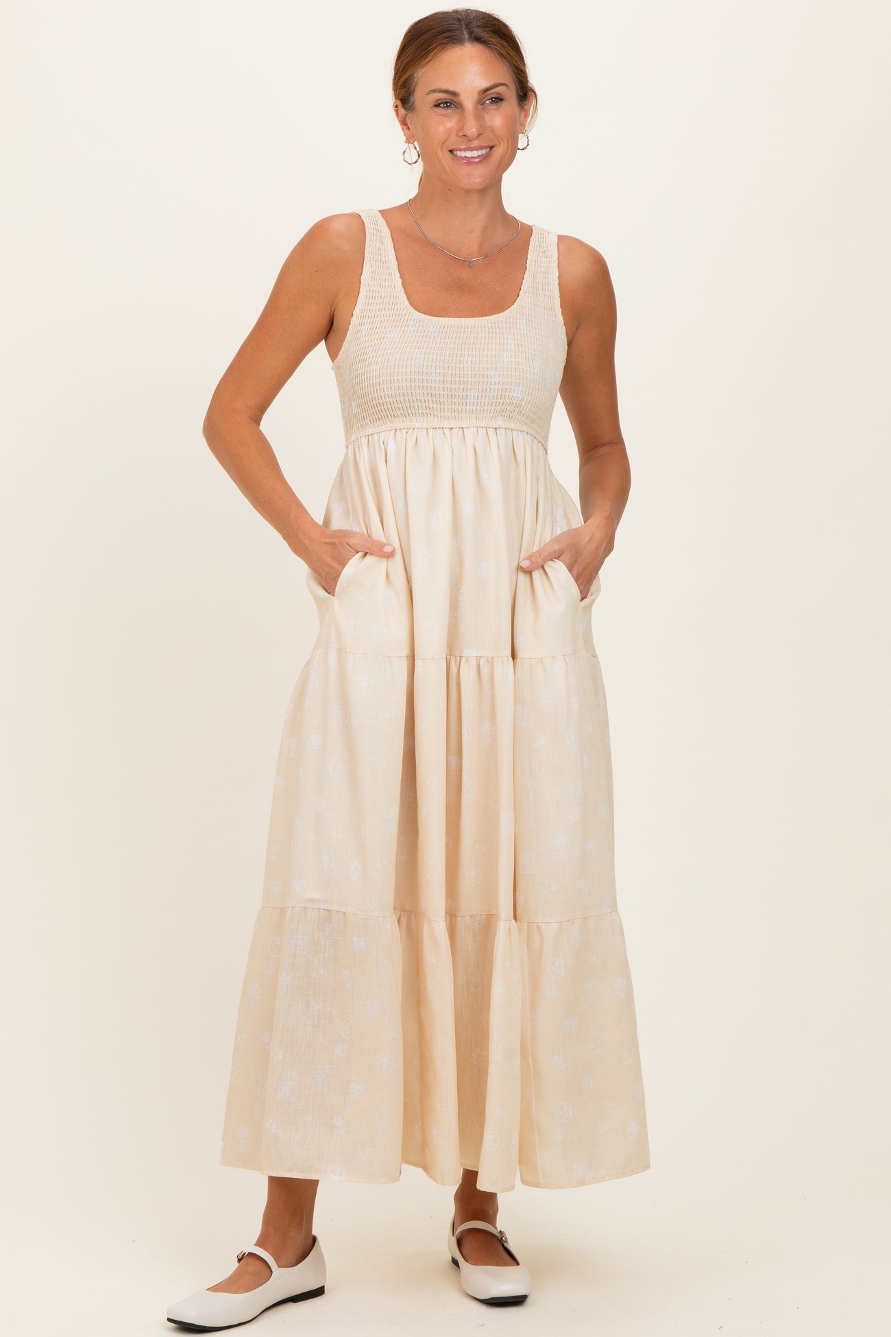 woman wearing a light beige maxi dress with a square neckline and pockets, styled with white shoes