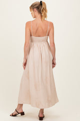 woman wearing a light beige maternity maxi dress with a smocked bodice and floral detailing, viewed from the back