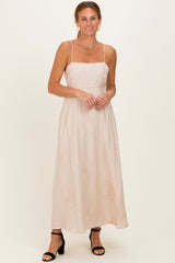 woman wearing a blush pink maxi dress with spaghetti straps and floral embroidery details