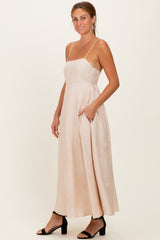 woman wearing a blush pink maxi dress with adjustable spaghetti straps and side pockets