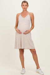 woman wearing a striped maternity dress with a v-neckline and baby bump, standing in white sneakers