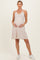woman wearing a striped maternity dress with a v-neckline and baby bump, standing in white sneakers