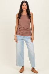woman wearing a brown ribbed tank top and light blue wide-leg jeans, standing with hands by her sides