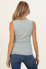 woman wearing a light green sleeveless maternity top with ribbed texture and a fitted silhouette